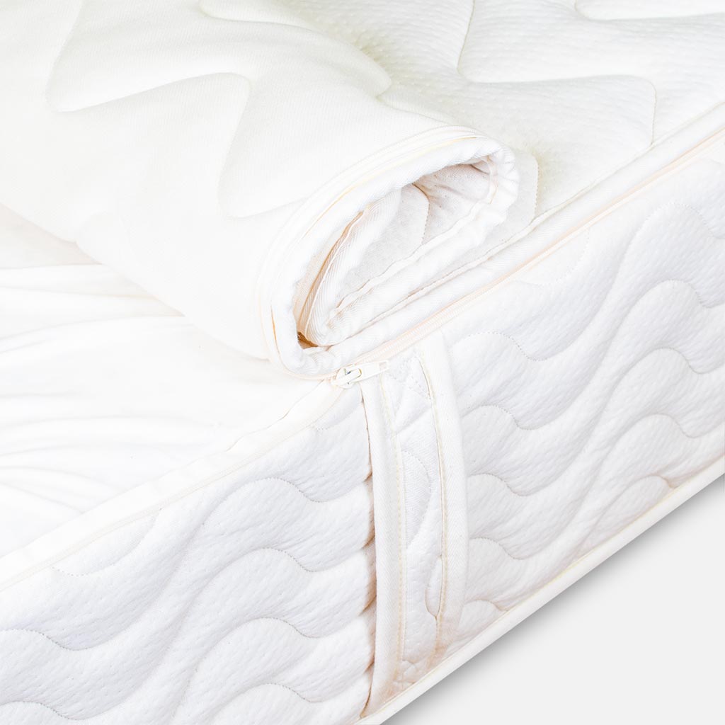 Close-up of a white quilt with gold accents on a light gray background